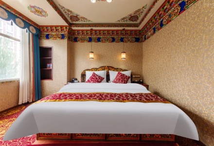 Tibetan style king bedroom with painted wooden frame at Gesar Hotel