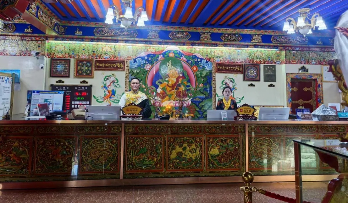 Hotel staff at front desk counter with ornate Tibetan mural