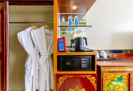 In room wardrobe with bathrobes safe box and kettle at Gesar Hotel