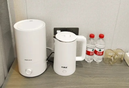 Electric kettle, humidifier, and bottled water on guest room desk