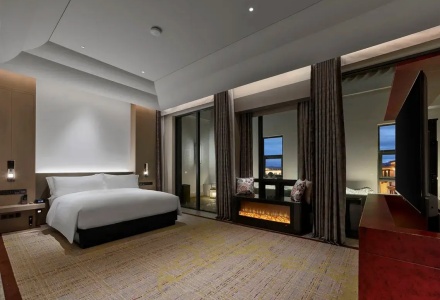 Premium executive suite bedroom with an electronic fireplace and king bed