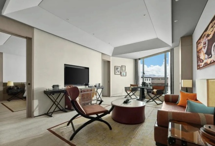 Spacious suite living area with a leather sofa, TV, and work desk