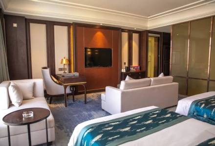 Modern twin guest room with sitting area and TV desk