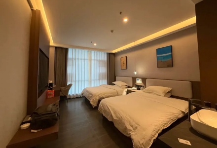 Spacious twin guest room with soft warm lighting at Western Inn Sheli Hotel