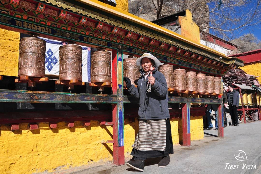 Tibetan granny spins the prayer wheels for praying