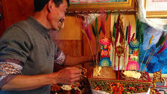 A local Tibetan was adding a butter sculpture on the Chemar box in his family