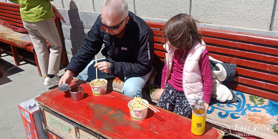 The father showed his cute daughter how to add chilli sauce into noodles