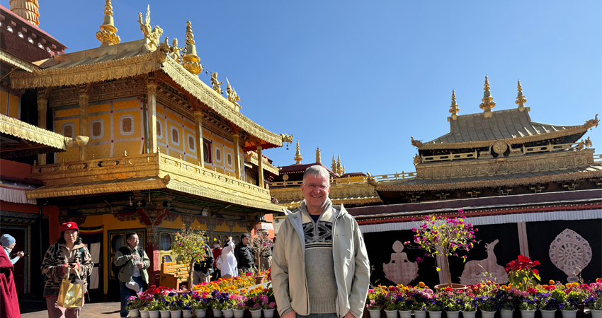 Tourist standing in front of golden rooftops at Jokhang Temple, Lhasa
