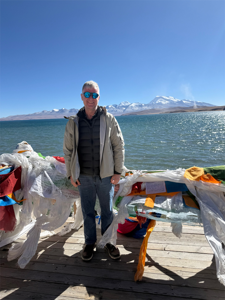 man at Lake Manasarovar with prayer flags