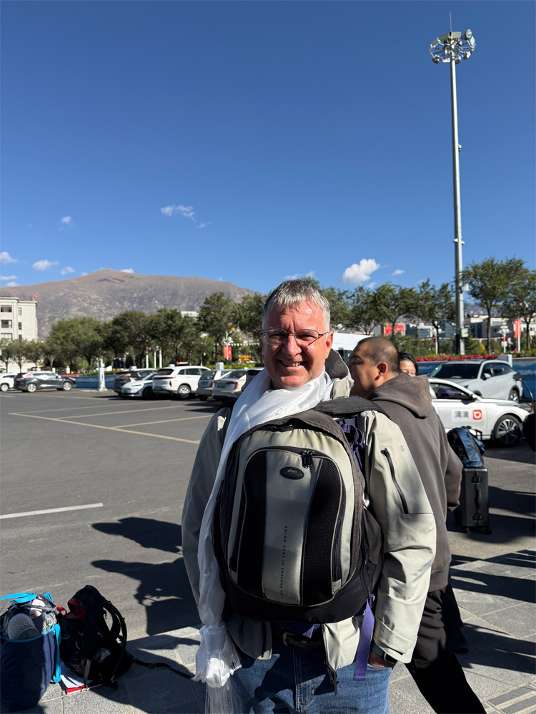 Local Tibetan guide greeting tourist with white ceremonial scarf in Lhasa