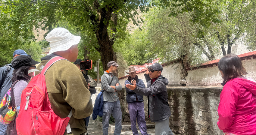 Local guide explaining monastery visit gestures in Lhasa