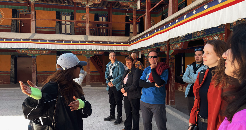 Local guide explaining Potala Palace courtyard to group of travelers