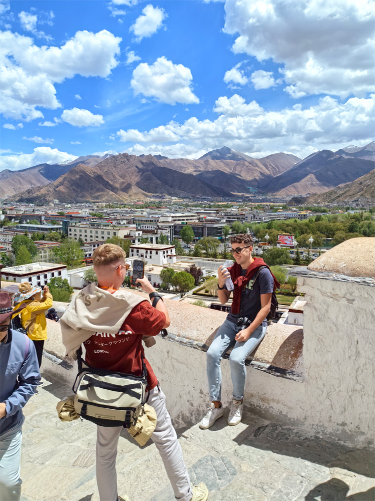 Travelers resting on Potala Palace stairs in Lhasa with oxygen canisters