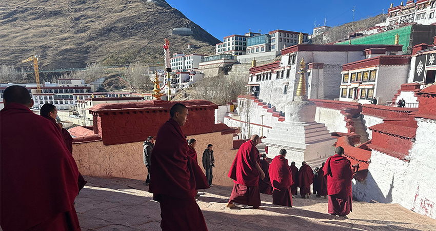 Tibetan monks in red robes walking through a monastery