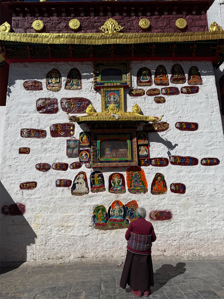 Tibetan pilgrim praying at holy wall altar