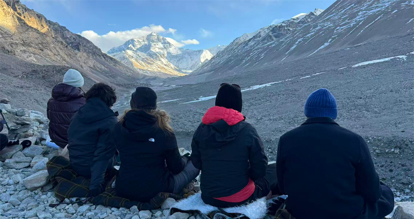 Group of travelers sitting at Tibet Everest Base Camp viewing Mount Everest panorama, high altitude Himalayan landscape in Tibet China
