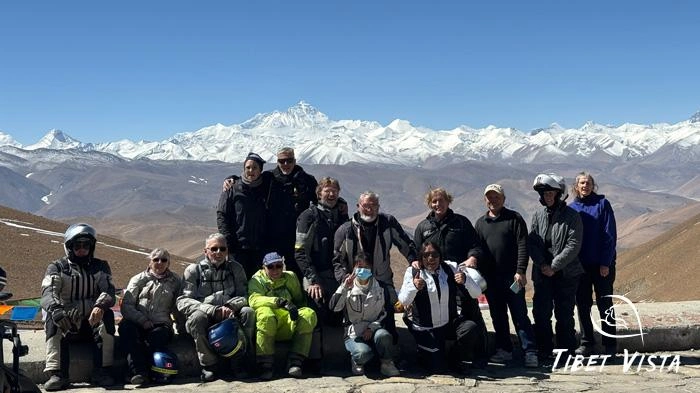 Group photo of motorcycle tour with Mountain Everest at Gawula Pass.