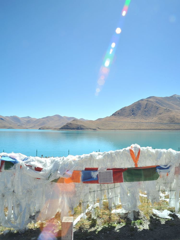 White khata scarves fluttering by Yamdrok Lake handrail