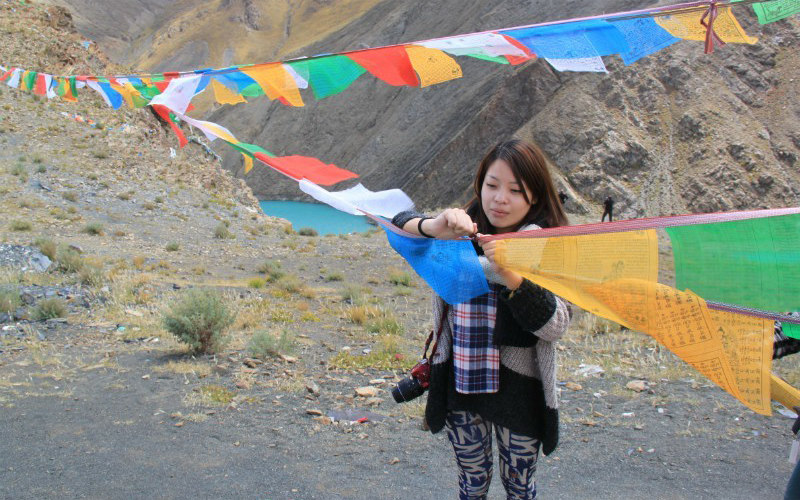 Gigi ties colorful prayer flags